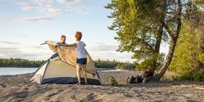 Un couple installe une tente au parc national de la Pointe-Taillon.