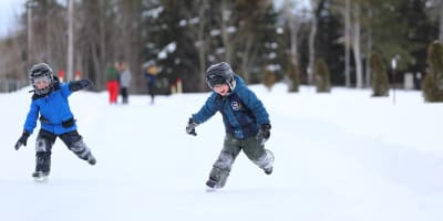 Two children are skating at the Dam-en-Terre Resort.