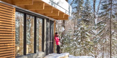 Une femme à l'extérieur d'un chalet du Parc national du Mont-Mégantic, en hiver.