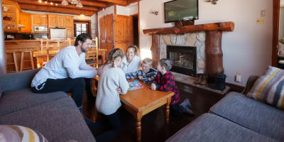 Une famille joue à des jeux de sociétés dans un chalet.