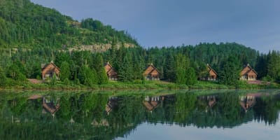 Peaceful lakeside cabins reflected in the calm water.