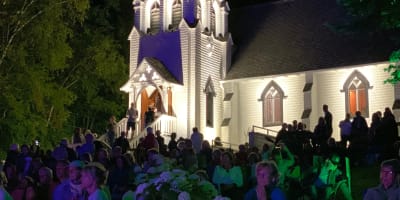 Chapelle du Lac - A crowd outside an illuminated white chapel at night