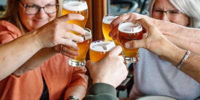 People around a table with pizza and beer from Des Cantons Microbrasserie.