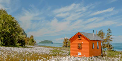 Orange tiny house by the St.Lawrence river in spring. 