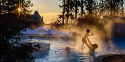 Family swimming in the outdoor pool in winter at Fairmont Le Manoir Richelieu.
