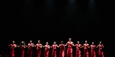 Festival des Arts de Saint-Sauveur - Dancers dressed in red are lined up on a dark stage.