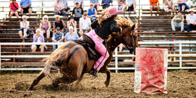 Woman participating in a barrel race at the Guigues Western Festival.