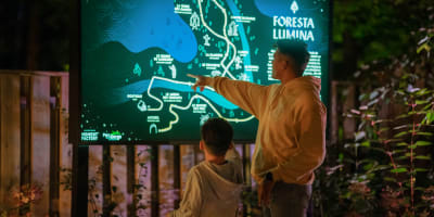 Foresta Lumina au Parc de la Gorge de Coaticook - A man and a boy point to an illuminated map.