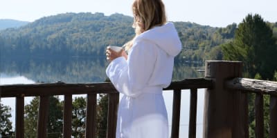 A young woman in a bathrobe enjoying her coffee on the balcony.