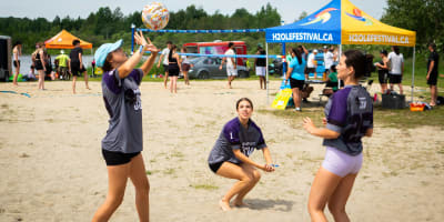 3 young women playing volleyball.