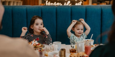 Two little girls eating breakfast at the hotel restaurant.