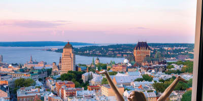 A woman waking up in a cozy bed with a spectacular view of Québec City.