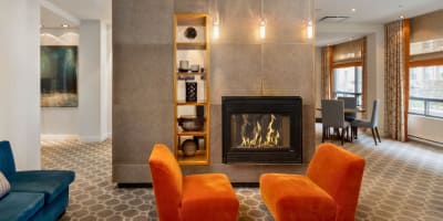 Hotel 2170 Lincoln - Deux chaises oranges devant un foyer allumé