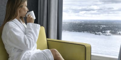 A woman sits on a couch, enjoying the view while sipping coffee.