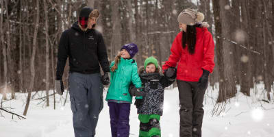 Family walking along a snow-covered forest trail.