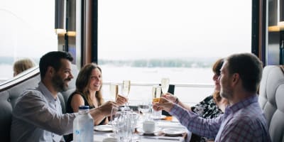 Hôtel Verso - Four adults sitting around a table in a restaurant with a view of the water.