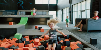 Une fille saute dans un bassin de blocs de mousse à iSaute.