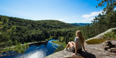 A hiker looking out at the horizon from a mountaintop. 