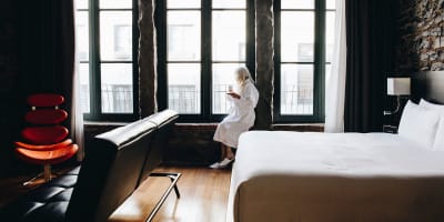 Le Petit Hôtel - Une personne en peignoir est assise sur le bord des fenêtres dans une chambre