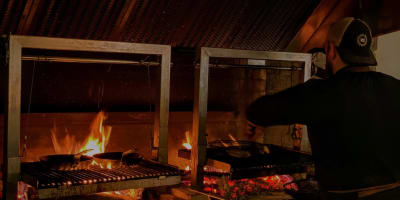 A cook preparing food over hot coals. 