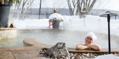 Woman in the outdoor spa at Manoir du Lac William in winter.