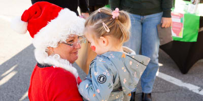Prévost Christmas Market - A woman dressed as Mother Christmas is holding a child in her arms.