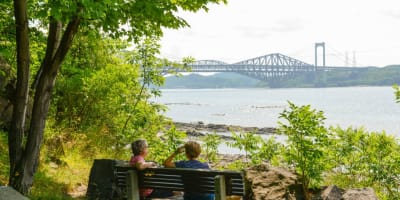 Deux personnes assises sur un banc l'été au Parc de la plage Jacques-Cartier.