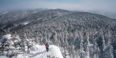 Hiker at the summit in winter at Parc d'environnement naturel de Sutton.