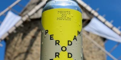 Perodam Microbrasserie Solidaire - Cannette de bière, un moulin en arrière-plan.