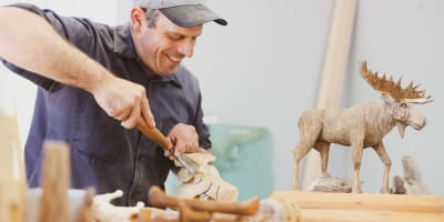 Sculpteur et orignal en bois.