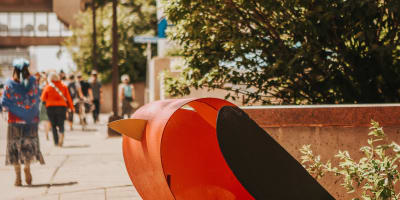 A sculpture of a bird on a sidewalk. 