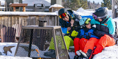 Family sitting at the foot of the mountain at Sommet Saint-Sauveur.