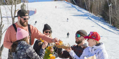 Friends are eating at the bottom of the Sommet Saint-Sauveur ski mountain.