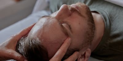 A man lying on his back is getting a head massage.