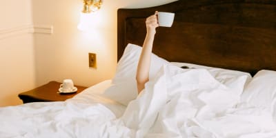 A person with a coffee in bed.