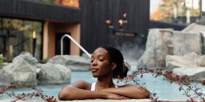Une femme dans un spa extérieur du Strøm Spa Nordique.