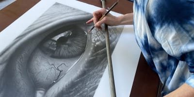 Tour des Arts - Une artiste travaille sur un dessin au fusain très détaillé d'un œil humain