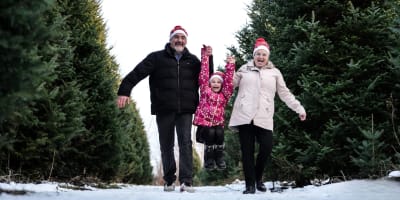 Une famille marche à côté de sapins au Village de Noël - Sapins Goupil.