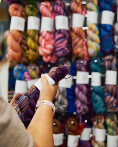 Twist Fibre Festival - A person holds a hank of yarn in front of a display stand.