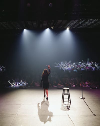 Just For Laughs MONTRÉAL - On a stage, a comedian is illuminated by spotlights.