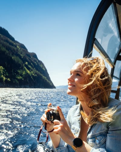 Les navettes maritimes du Fjord - Une femme sur un bateau tient une caméra.