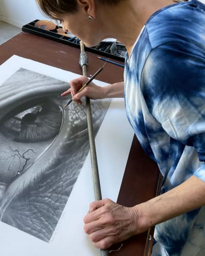 Tour des Arts - Une artiste travaille sur un dessin au fusain très détaillé d'un œil humain