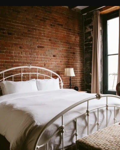 Bed in a room with an exposed brick wall at Auberge du Vieux-Montréal