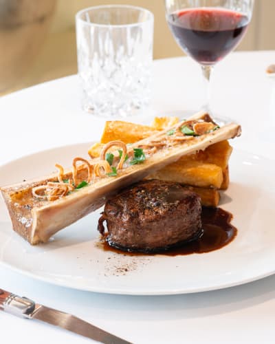 Gourmet plate featuring beef tenderloin, bone marrow, and brown sauce.