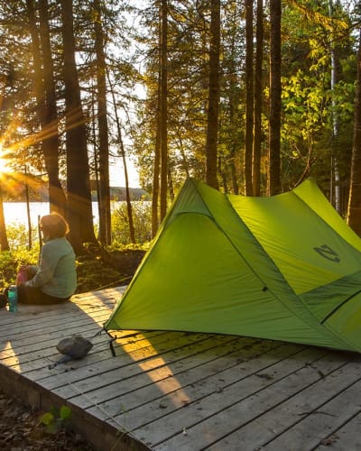 Un couple assis à côté d'une tente verte au Parc national du Lac-Témiscouata.
