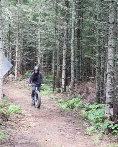 Centre récréotouristique des Hautes Terres - An individual riding a fatbike in a forest