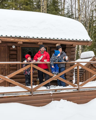 Une famille sur le balcon enneigé d'un chalet du parc national d’Aiguebelle.
