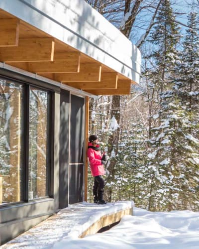 Une femme à l'extérieur d'un chalet du Parc national du Mont-Mégantic, en hiver.