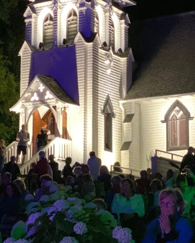 Chapelle du Lac - A crowd outside an illuminated white chapel at night