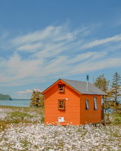 Orange tiny house by the St.Lawrence river in spring. 